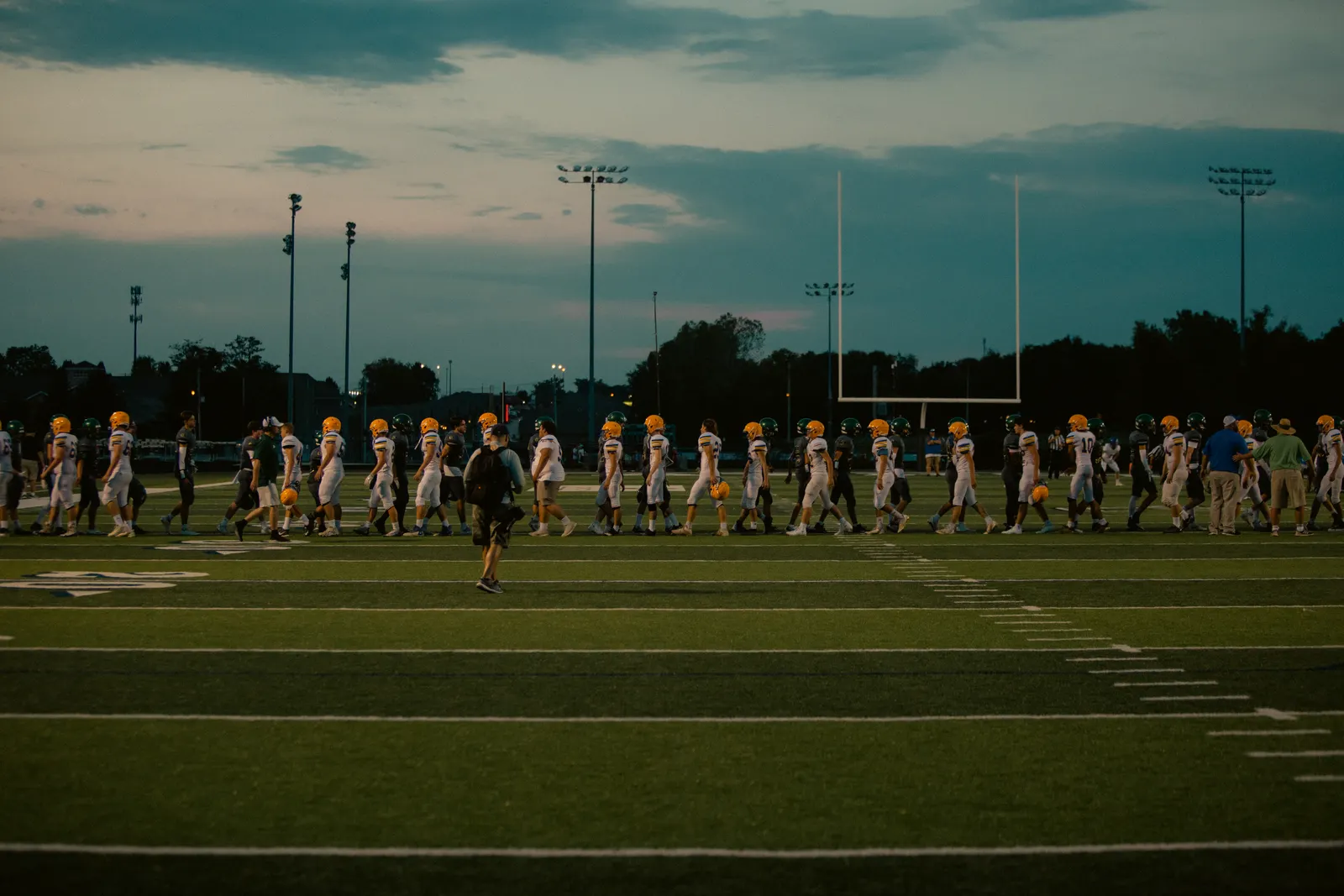 Players walking off a football field at dusk